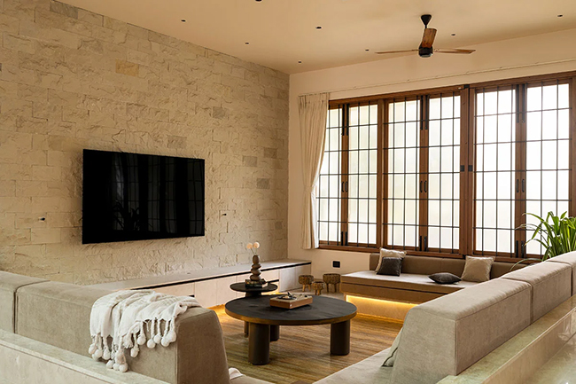 Tường đá thô mộc, ghế sofa lớn và cửa sổ chia ô gỗ